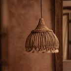 Woven pendant light hanging against a textured wall.