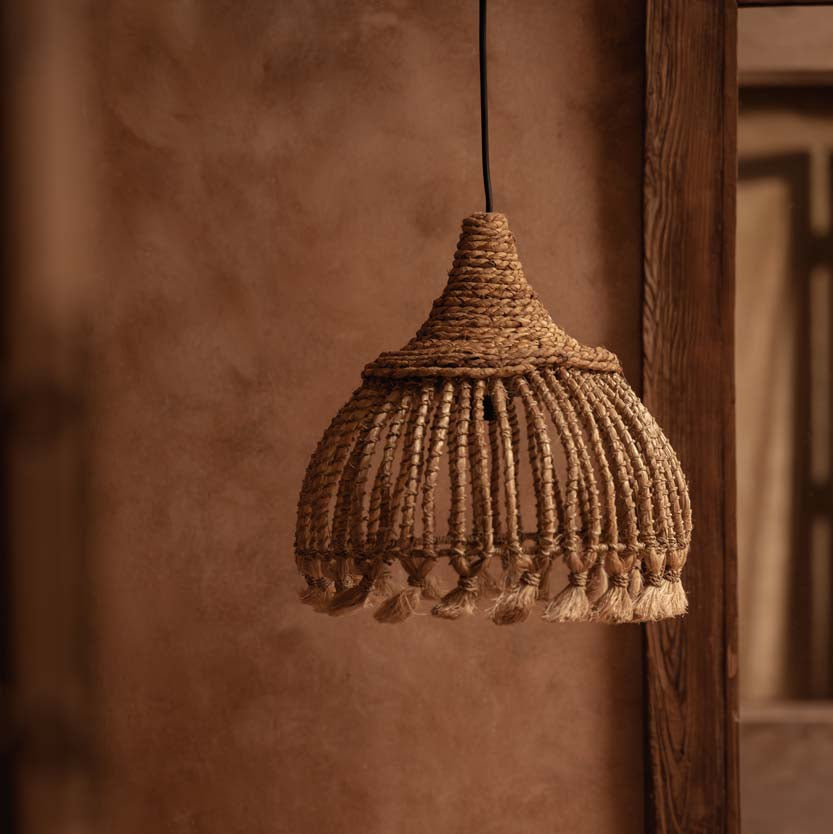 Woven pendant light hanging against a textured wall.